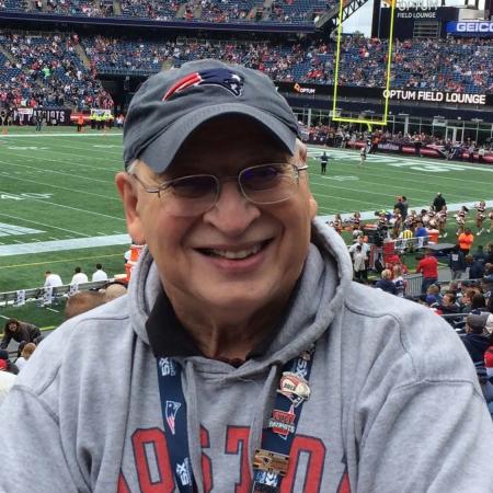 A white man in Patriots gear against the backdrop of Gillette Stadium