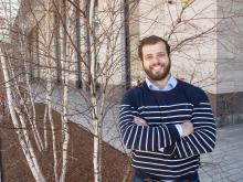 Portrait of Theo Mouratidis standing in front of young birch trees on the MIT campus.